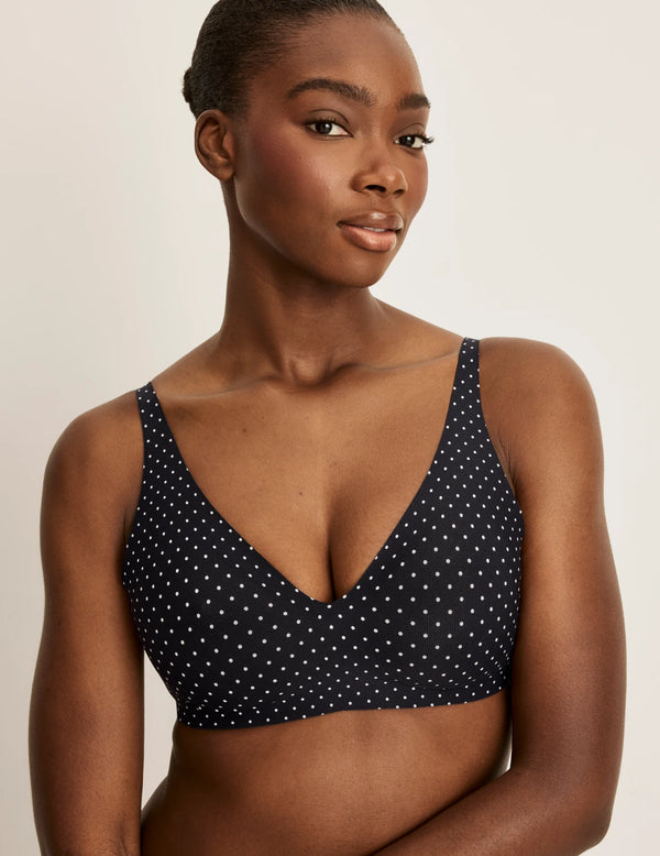 Orlane is a 32DD and wearing KNIX S+ | Front view of model wearing the Revolution V-Neck Bra, highlighting the neckline, strap design, and smooth silhouette | Black with White Polka Dot